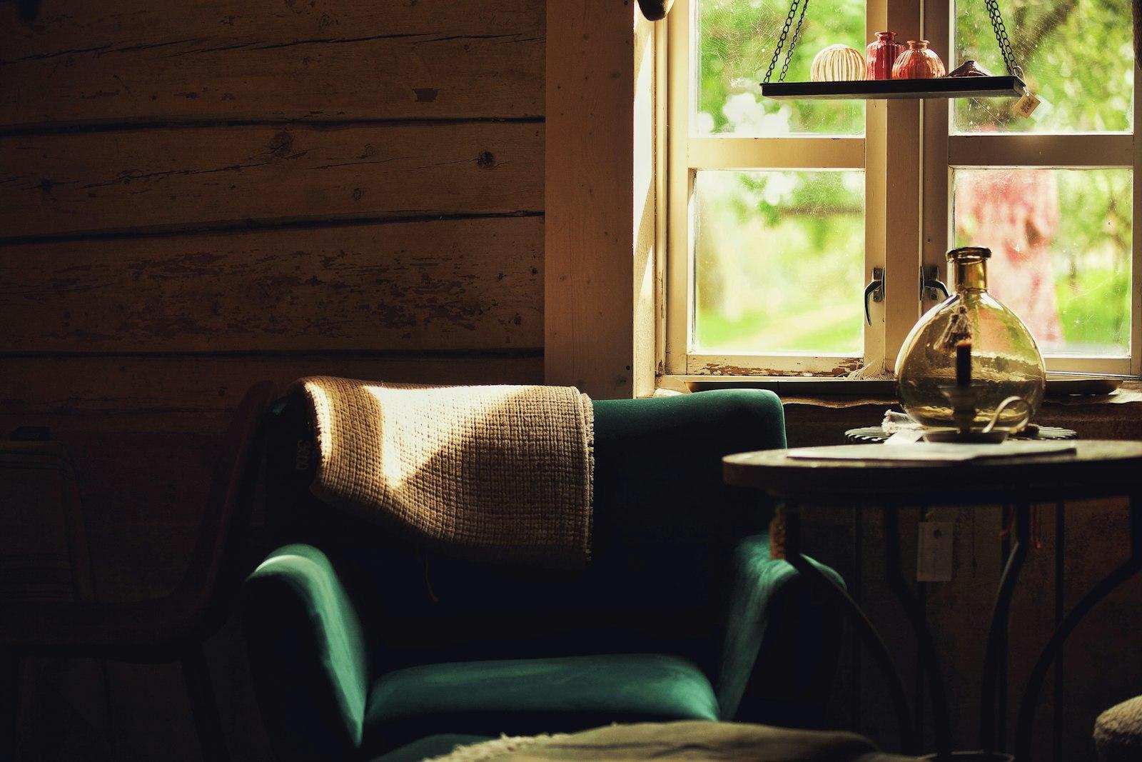 A chair and small table beside a window in a quiet, warmly lit room