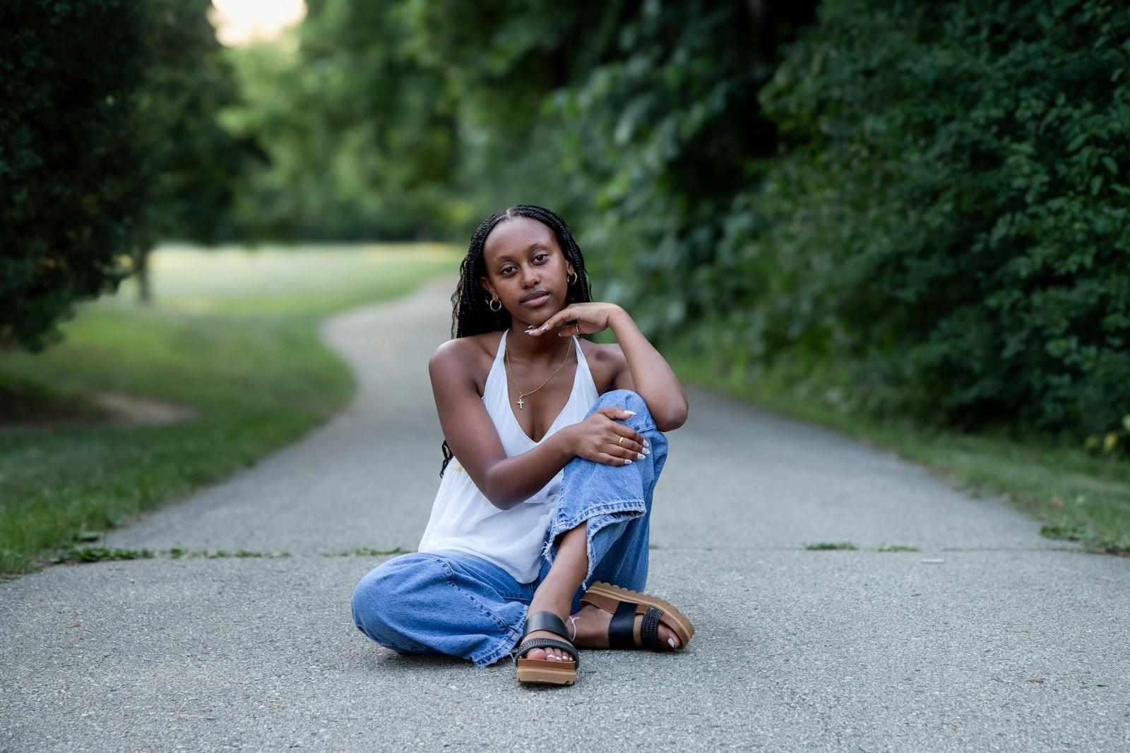 A woman sitting on a quiet path outdoors, thinking