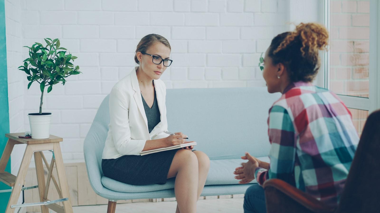 A therapist and a client sitting facing each other in a bright room